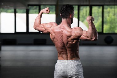 İyi eğitilmiş vücudunu gösteren genç bir adamın portresi - kaslı atletik vücut geliştirici spor sonrası vücut geliştirme modelliği pozu