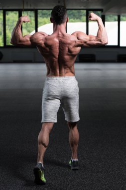 İyi eğitilmiş vücudunu gösteren genç bir adamın portresi - kaslı atletik vücut geliştirici spor sonrası vücut geliştirme modelliği pozu