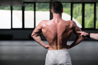 Yakışıklı Genç Adam Spor Salonunda Güçlü Duruyor ve Kaslarını Geriyor - Kas Atletik Vücut Geliştirici Spor Sonrası Spor Pozisyonu