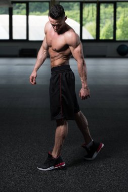 Yakışıklı Genç Adam Spor Salonunda Güçlü Duruyor ve Kaslarını Geriyor - Kas Atletik Vücut Geliştirici Spor Sonrası Spor Pozisyonu