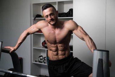 Yakışıklı ve çekici bir genç adam. Vücut kasları spor salonunda dinleniyor.