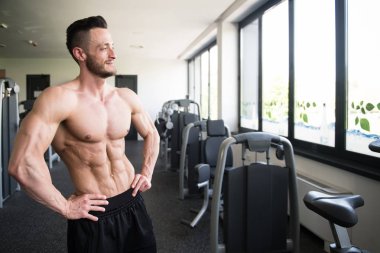 Yakışıklı Genç Adam Spor Salonunda Güçlü Duruyor ve Kaslarını Geriyor - Kas Atletik Vücut Geliştirici Spor Sonrası Spor Pozisyonu