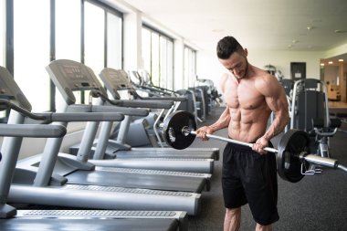 Spor salonunda bilardo oynayan sporcu halterle kıvrılıyor.