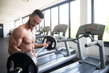 Spor salonunda bilardo oynayan sporcu halterle kıvrılıyor.