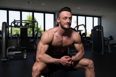 Yakışıklı ve çekici bir genç adam. Vücut kasları spor salonunda dinleniyor.