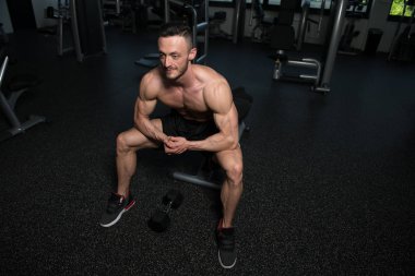 Yakışıklı ve çekici bir genç adam. Vücut kasları spor salonunda dinleniyor.