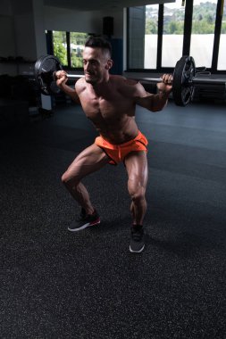 Spor salonundaki güçlü adam halterle bacak egzersizi yapıyor kaslı atletik vücut geliştirici spor mankeni egzersizi.