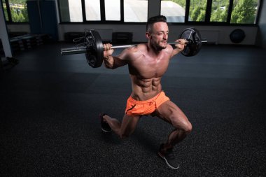 Spor salonundaki güçlü adam halterle bacak egzersizi yapıyor kaslı atletik vücut geliştirici spor mankeni egzersizi.
