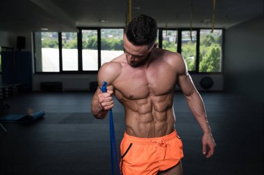 Egzersiz Fitness vücut geliştirme eğitim bir parçası olarak bir direniş Band içinde jimnastik salonu ile çekici bir adam