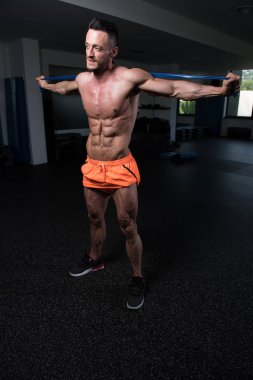 Egzersiz Fitness vücut geliştirme eğitim bir parçası olarak bir direniş Band içinde jimnastik salonu ile çekici bir adam