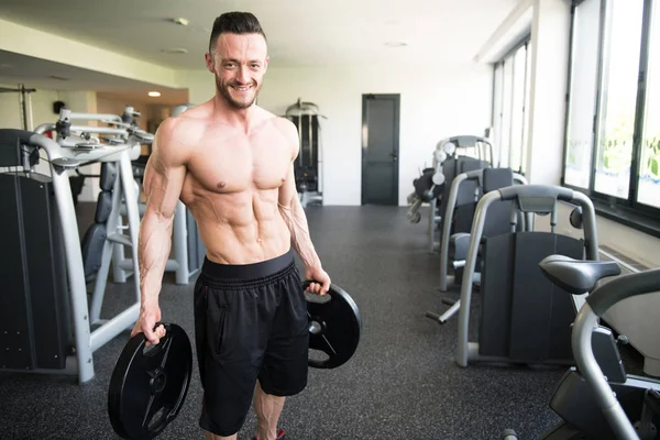 Elinde ağırlıkları olan genç bir adamın portresi.