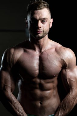 Yakışıklı Genç Adam Spor Salonunda Güçlü Duruyor ve Kaslarını Geriyor - Kas Atletik Vücut Geliştirici Spor Sonrası Spor Pozisyonu