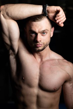 İyi eğitilmiş vücudunu gösteren genç bir adamın portresi - kaslı atletik vücut geliştirici spor sonrası vücut geliştirme modelliği pozu
