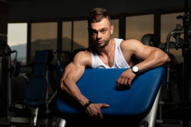 Yakışıklı ve çekici bir genç adam. Vücut kasları spor salonunda dinleniyor.