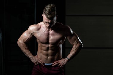 İyi eğitilmiş vücudunu gösteren genç bir adamın portresi - kaslı atletik vücut geliştirici spor sonrası vücut geliştirme modelliği pozu