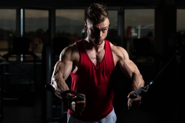 Güzel kaslı vücut geliştirici. Spor salonunda kablolu TV ile Göğüs Üstünde Ağırlık Egzersizi Yapıyor.