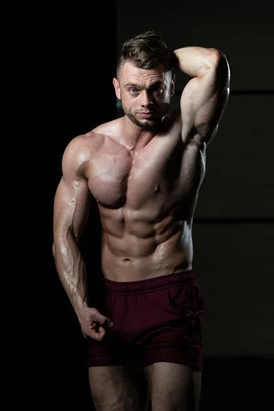 Schöner Junger Mann Der Stark Fitnessstudio Steht Und Die Muskeln — Stockfoto