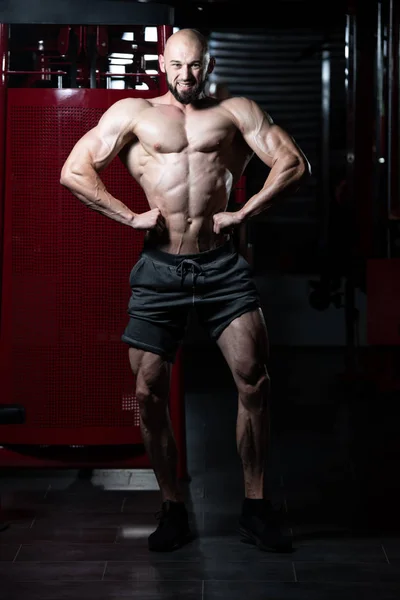 Uomo muscolare che flette i muscoli in palestra — Foto Stock