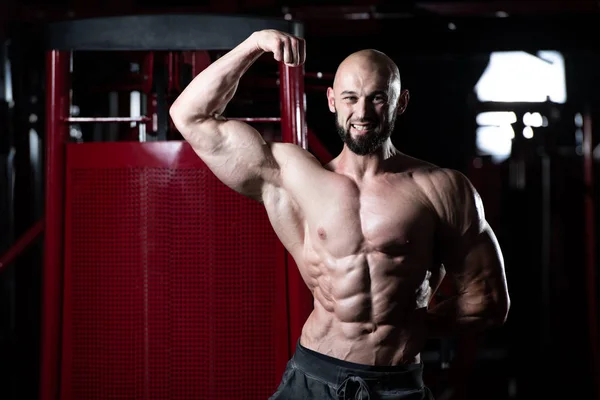 Uomo muscolare che flette i muscoli in palestra — Foto Stock