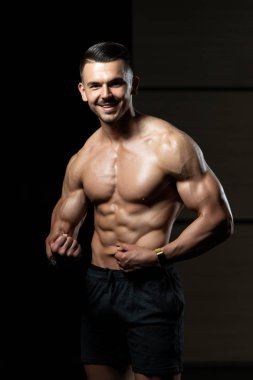 Kaslı adam kaslarını ölçüyor.
