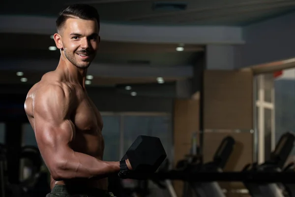 Kulturista cvičení biceps s činkami — Stock fotografie