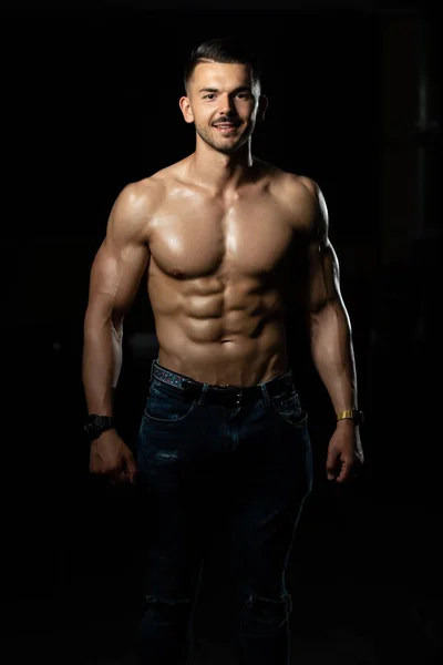 Jeune bodybuilder en jeans muscles flexibles — Photo