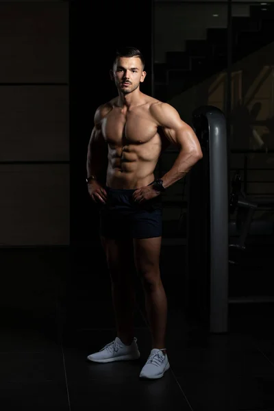 Homem muscular flexionando músculos no ginásio — Fotografia de Stock