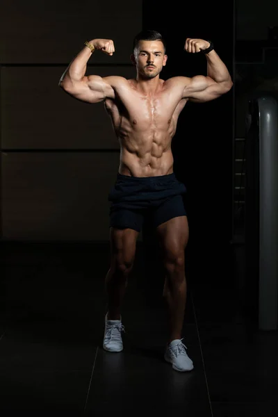 Culturista realizando frente doble bíceps Pose en el gimnasio — Foto de Stock