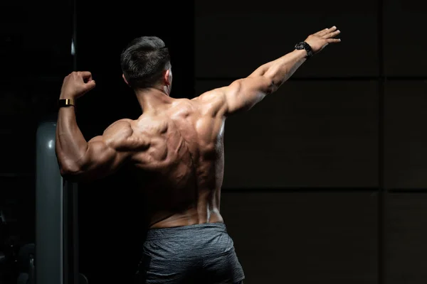 Homem muscular que flexiona a dose dos músculos traseiros — Fotografia de Stock