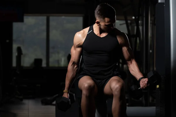 Homem muscular exercício bíceps com halteres — Fotografia de Stock