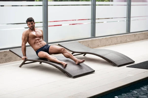 Hombre descansando en tumbonas junto a la piscina — Foto de Stock