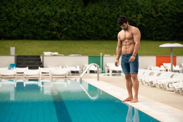 Jeune homme Macho regardant à la piscine extérieure — Photo