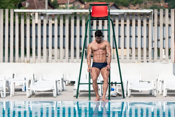 Jeune homme regardant sauveteur à la piscine extérieure — Photo