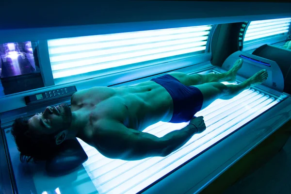 Junger muskulöser Mann im Solarium eines Schönheitssalons — Stockfoto