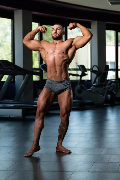 Muskulöser Mann schlägt auf hinteren doppelten Bizeps ein — Stockfoto