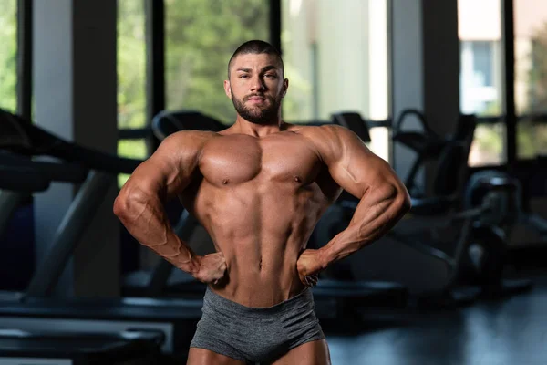 Schöner muskulöser Mann lässt Muskeln im Fitnessstudio spielen — Stockfoto