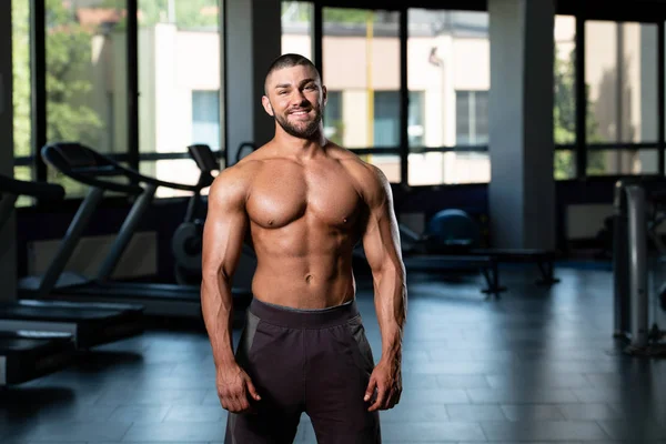 Uomo muscolare che flette i muscoli in palestra — Foto Stock