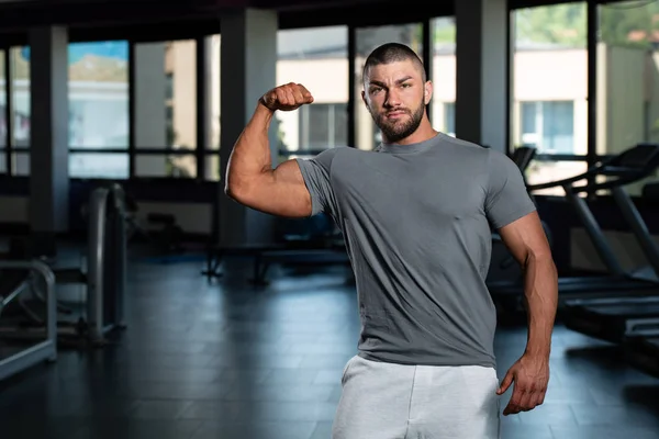 Muskulös man poserar i grå T-shirt — Stockfoto