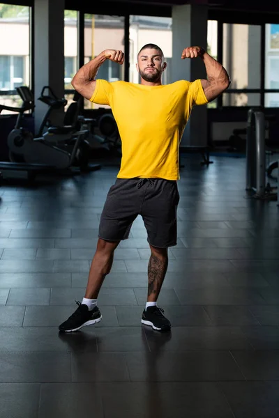 Muskulös man poserar i gul T-shirt — Stockfoto