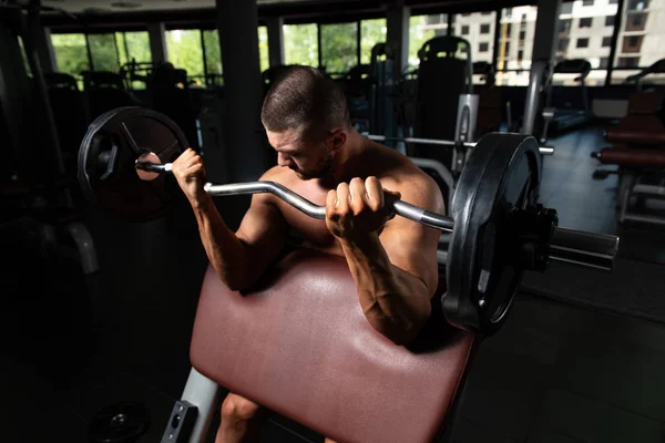 Atleta ejercitando bíceps en un gimnasio — Foto de Stock