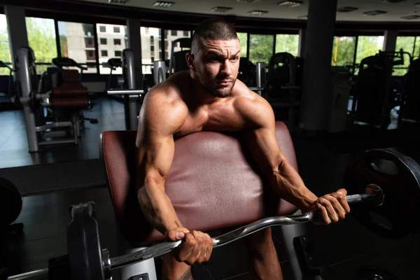 Homem no ginásio exercício bíceps com Barbell — Fotografia de Stock