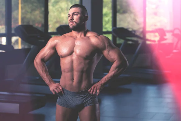 Schöner muskulöser Mann lässt Muskeln im Fitnessstudio spielen — Stockfoto