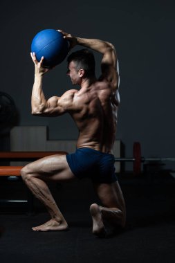 Bodybuilder Flexing Muscles With Medicine Ball