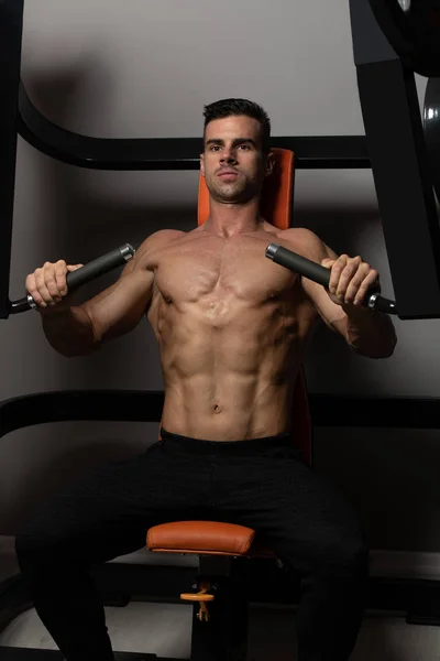 Jovem homem exercitando o peito no ginásio — Fotografia de Stock