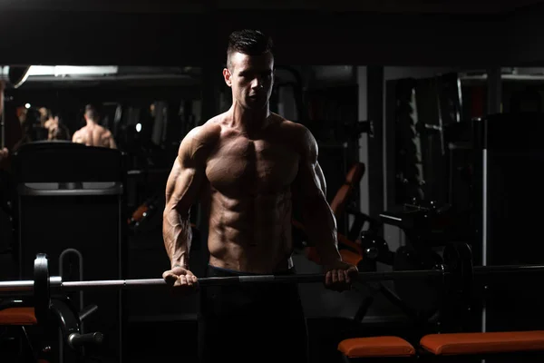 Homem no ginásio exercício bíceps com Barbell — Fotografia de Stock