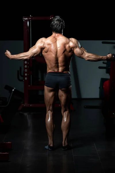 Muscular hombre flexión músculos trasero doble bíceps Pose —  Fotos de Stock