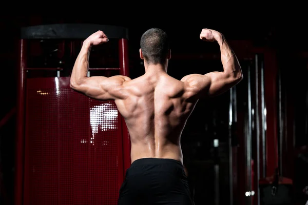 Biceps představují mladého muže v tělocvičně — Stock fotografie