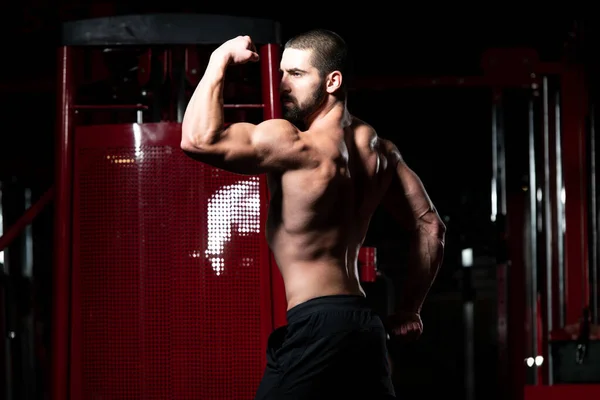 Muskulöser Mann lässt Muskeln in Turnhalle spielen — Stockfoto