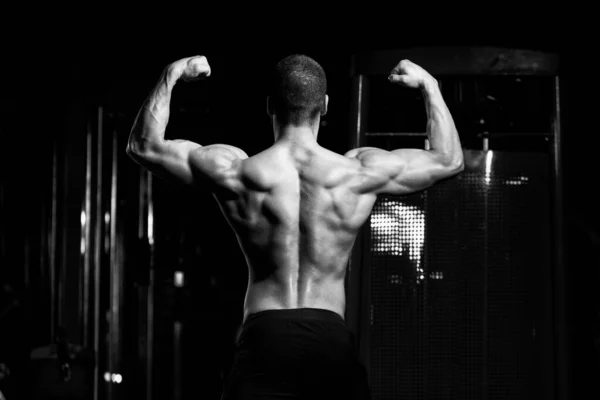 Pose de bíceps de un hombre joven en el gimnasio —  Fotos de Stock