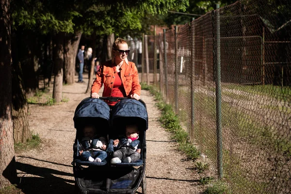 年轻的母亲带着孩子散步 用漂亮的婴儿车抱着孩子 — 图库照片